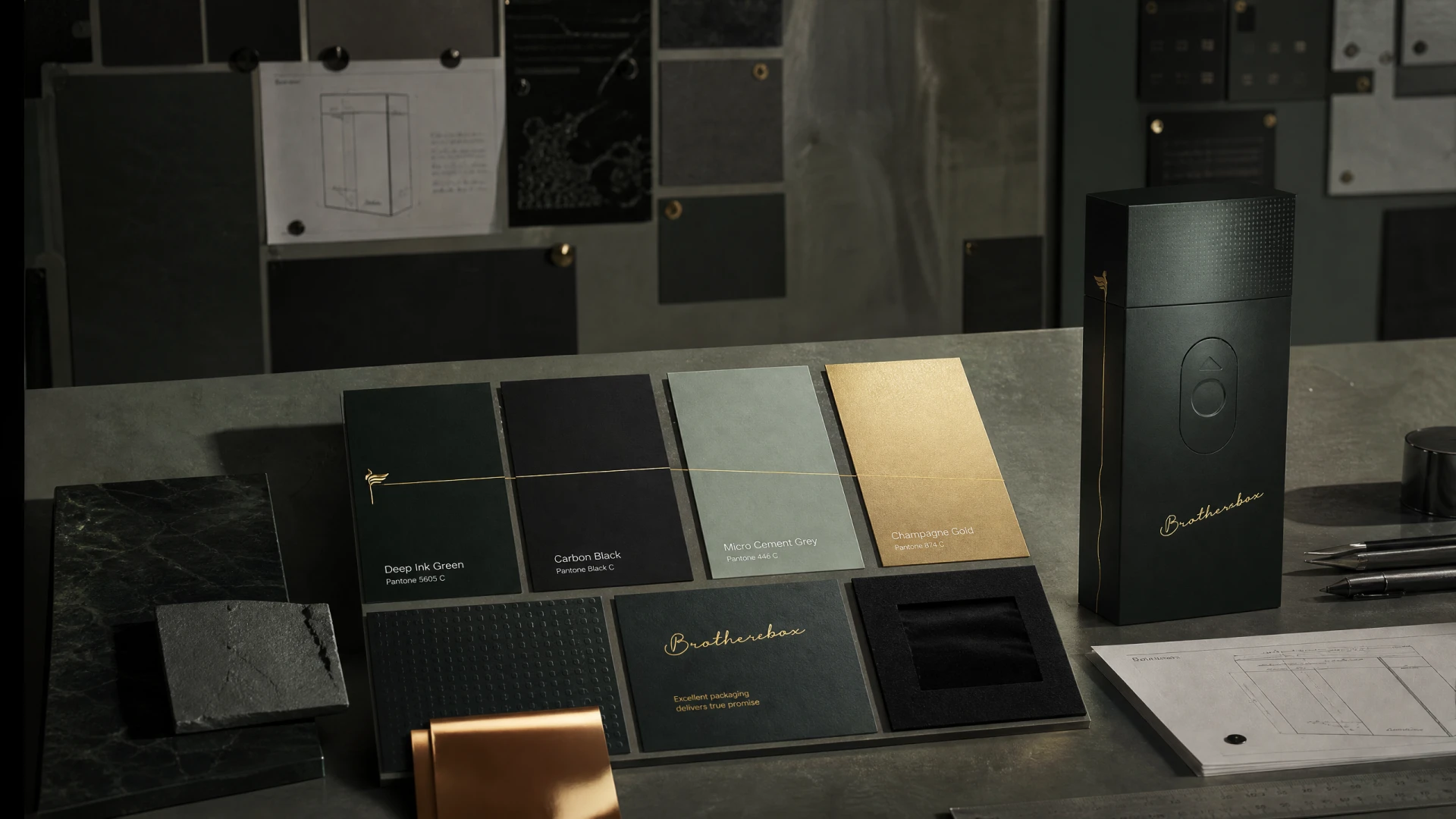 Material‑sample board displaying matte paper, hot‑foil gold, embossed texture and finished packaging box on design workspace